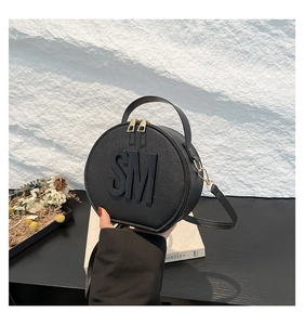 Macro detail of black circular bag featuring Saffiano texture and golden metal zippers