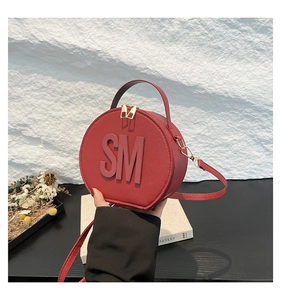 Detailed macro view of the red round crossbody bag with SM embossed logo and gold hardware