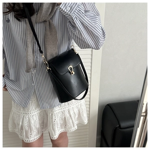 Détail du sac seau en cuir noir avec un fermoir en U doré pour un style quotidien chic