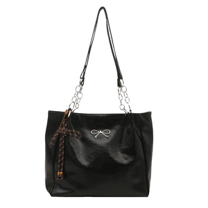 Classic black tote bag with silver bow accent and leather chain strap on white background