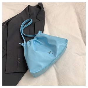 Dettaglio borsa a secchiello azzurra con coulisse e piccolo fiocco in metallo su pelle PU