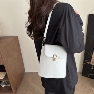 Sac seau blanc minimaliste avec fermoir doré porté à l'épaule pour un style chic