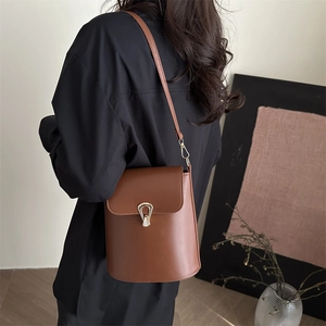Sac seau en cuir marron avec boucle dorée présenté dans un décor intérieur épuré