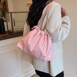 Borsa a secchiello plissettata rosa con coulisse e fiocco argento indossata nel caffè