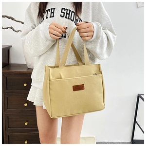 Close-up of beige canvas handbag with leather SPORT tag and practical zipper pocket