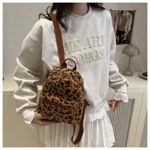 Detail of trendy leopard print mini backpack with adjustable straps worn by a model