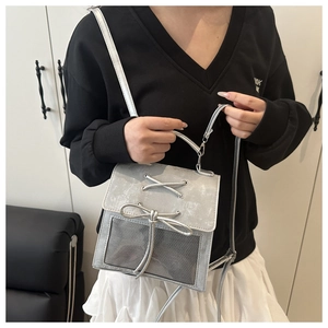 Detail showing the silver-grey crossbody bag with bow tie ribbon and mesh fabric texture