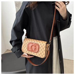 Detail of vintage crossbody bag with floral pattern and embossed G logo on black coat