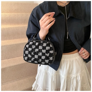 Close-up of black and white checkered small handbag with unique frayed fabric texture details