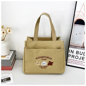 Close-up of khaki canvas tote with three embroidered bears and a convenient front pocket