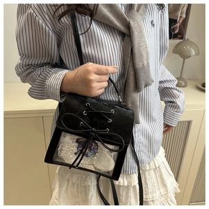 Detail of black velvet ita bag with ribbon cross straps and transparent window for badges