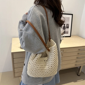 Beige woven bucket tote bag with brown leather handles for summer casual outfits