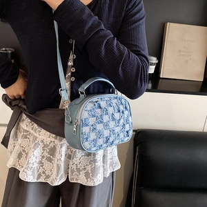 Blue denim checkerboard handbag with adjustable shoulder strap worn by a model