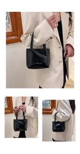 Détail de la finition en cuir verni noir brillant avec texte blanc sur le sac fourre-tout
