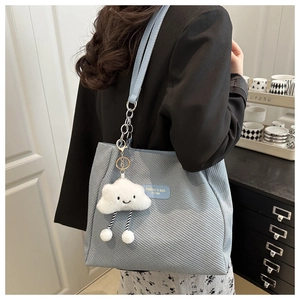 Close-up of light blue tote bag with twill texture and cute cloud plush pendant accessory