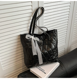 Détail du sac cabas matelassé noir avec nœud en dentelle et breloque papillon doré