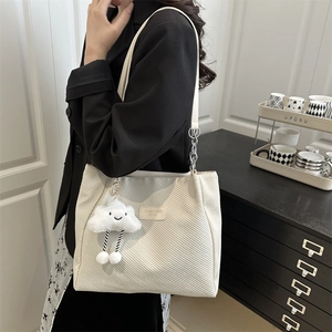 White corduroy tote bag with cloud charm and metal chain strap shown on shoulder