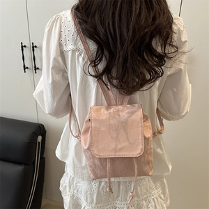 Pink mini backpack with pleated pearlescent texture and drawstring closure on a model