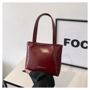 Détail du sac cabas bordeaux en cuir verni avec texture plissée brillante et texte argenté