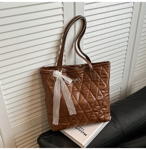 Détail du sac cabas matelassé marron avec nœud en dentelle blanche et cuir souple poli