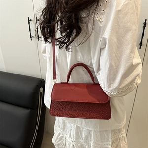 Vintage red textured crossbody bag with snake pattern flap and elegant top handle strap