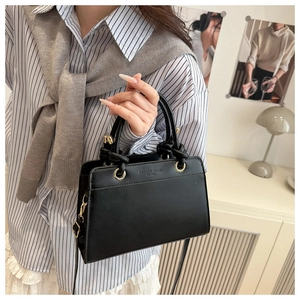 Detail of black PU leather tote bag with FASHION TREND embossed text held by a model