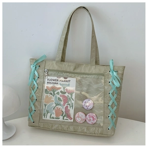 Detail of light green pleated tote bag with clear PVC window and blue ribbon ties