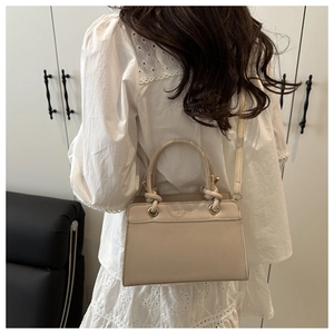 Detail view of beige trapezoid handbag with wrap handles and Fashion Trend embossing