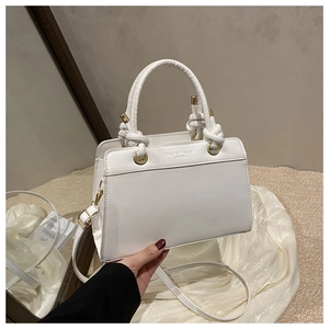 Detail of white leather tote bag showing fine litchi texture and gold hardware accents