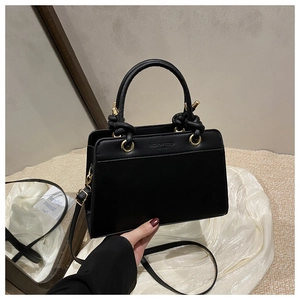 Detail of black leather tote bag with vintage gold hardware and knotted handle accents