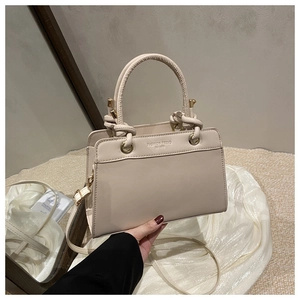 Detail view of the structured cream tote bag with circular handles and printed fashion text