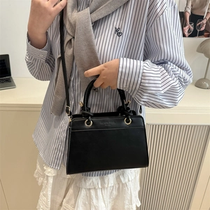 Minimalist black leather tote bag with embossed lettering and detachable shoulder strap