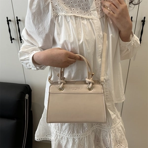 Minimalist beige leather tote bag with thick handles and adjustable shoulder strap for women