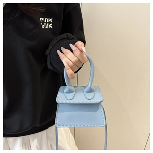 Detail view of a trendy light blue mini square handbag with top handle and strap.