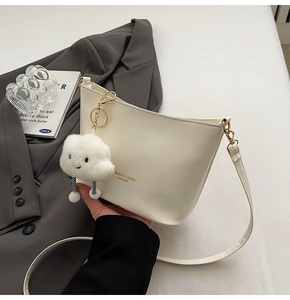 Close-up of white leather bucket bag with fashion lettering and cute cloud charm detail