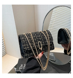 Gros plan sur le tissu en tweed noir aux fils dorés et boucle métallique ovale