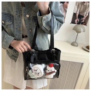 Detail of a black leather tote bag featuring a transparent PVC front pocket for plush toys