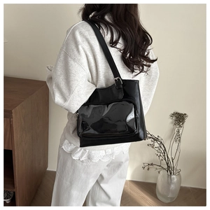 Detail of black glossy shoulder bag with transparent PVC pocket and adjustable metal buckle