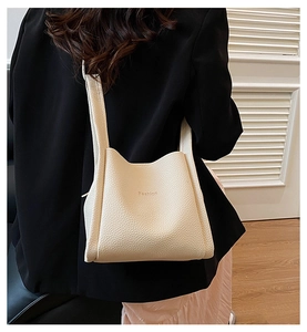 Detail view of cream-white bucket bag with lychee texture and embossed Fashion logo