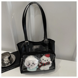 Close-up of large black PU tote bag featuring transparent PVC window with plush dolls inside