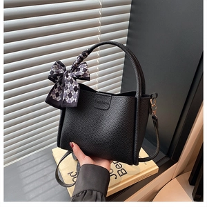 Close-up of black lychee grain leather bucket bag with fashion embossing and scarf