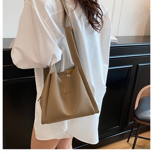 Detail view of the light brown bucket bag featuring pebble grain texture and soft side pleats