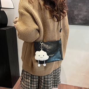 Black bucket shoulder bag with gold logo and white plush cloud charm on a model