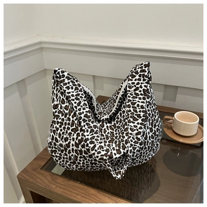 Close-up of leopard print canvas tote bag featuring white zipper and wide shoulder strap