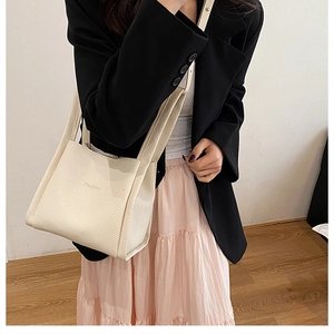 Chic beige lychee leather bucket tote bag styled with a black blazer and pink skirt