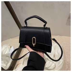 Détail du sac à main noir en similicuir avec fermoir doré et poignée supérieure élégante