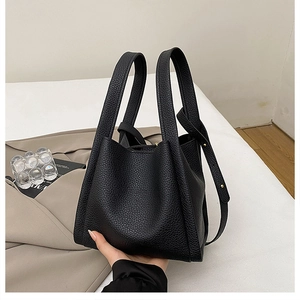 Detail of black lychee grain leather bucket bag with top handle and fashion stamp