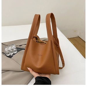 Detailed close-up of brown litchi pattern leather bucket bag with fashion embossing