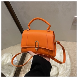 Détail du mini sac orange avec fermoir en U doré et poignée ronde rigide chic