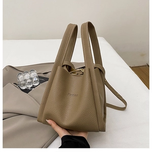 Detailed macro view of litchi texture leather and double handles on the khaki bucket bag